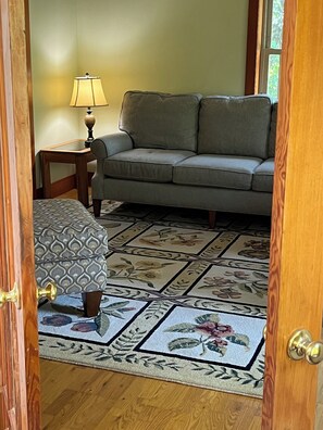 A room with a grey sofa, a patterned rug, and a lamp.