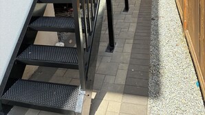 A set of outdoor stairs with a metal handrail leading to a wooden deck.