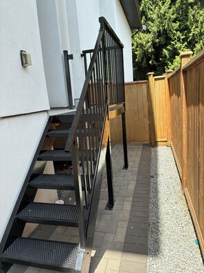 A set of outdoor stairs with a metal handrail leading to a wooden deck.