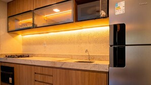 Una cocina con armarios de madera, un refrigerador de acero inoxidable, un lavamanos doble y una estufa a gas.