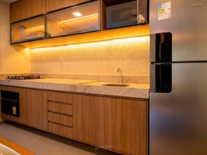 A kitchen with wooden cabinets, a stainless steel refrigerator, a double sink, and a gas stove.