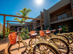 A row of bicycles with baskets, a wooden pergola, and a building with balconies. - Cond Azuk Patacho: Leisure and Beach by MME (Porto de Pedras)