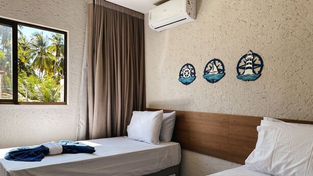 Habitación de hotel con dos camas, una ventana con cortinas y adornos en la pared.