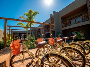 A row of bicycles with baskets, a wooden pergola, and a building with balconies.
