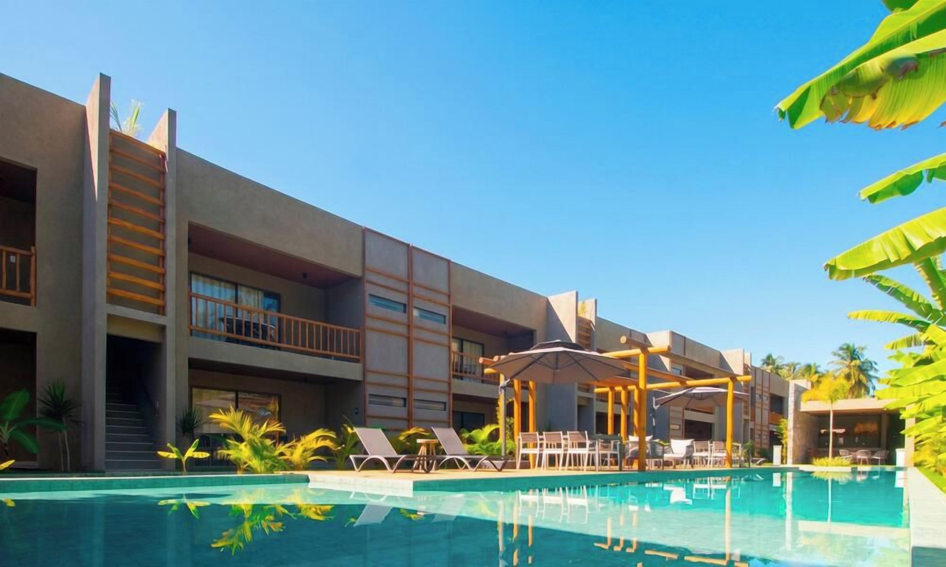 Un hotel con piscina, lettini e una zona salotto coperta.