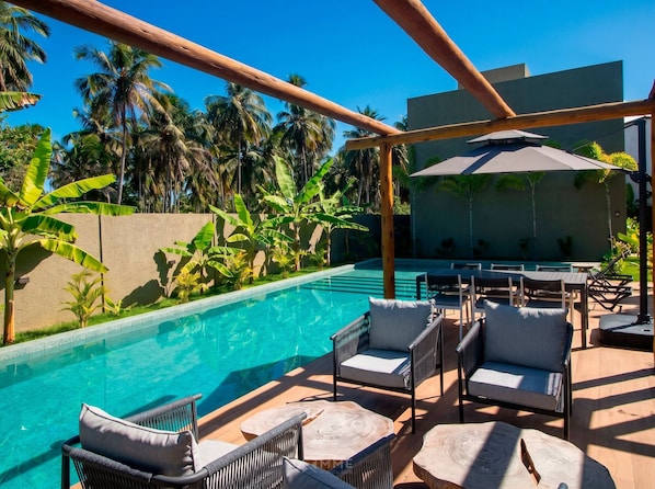A poolside area with lounge chairs, a table, and a view of the pool.