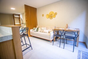 Ein modernes Wohnzimmer mit einer Couch, einem Esstisch, Stühlen und einer Wanddekoration.
