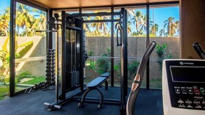 Un gimnasio con equipo de ejercicio, una banca y un panel de control.