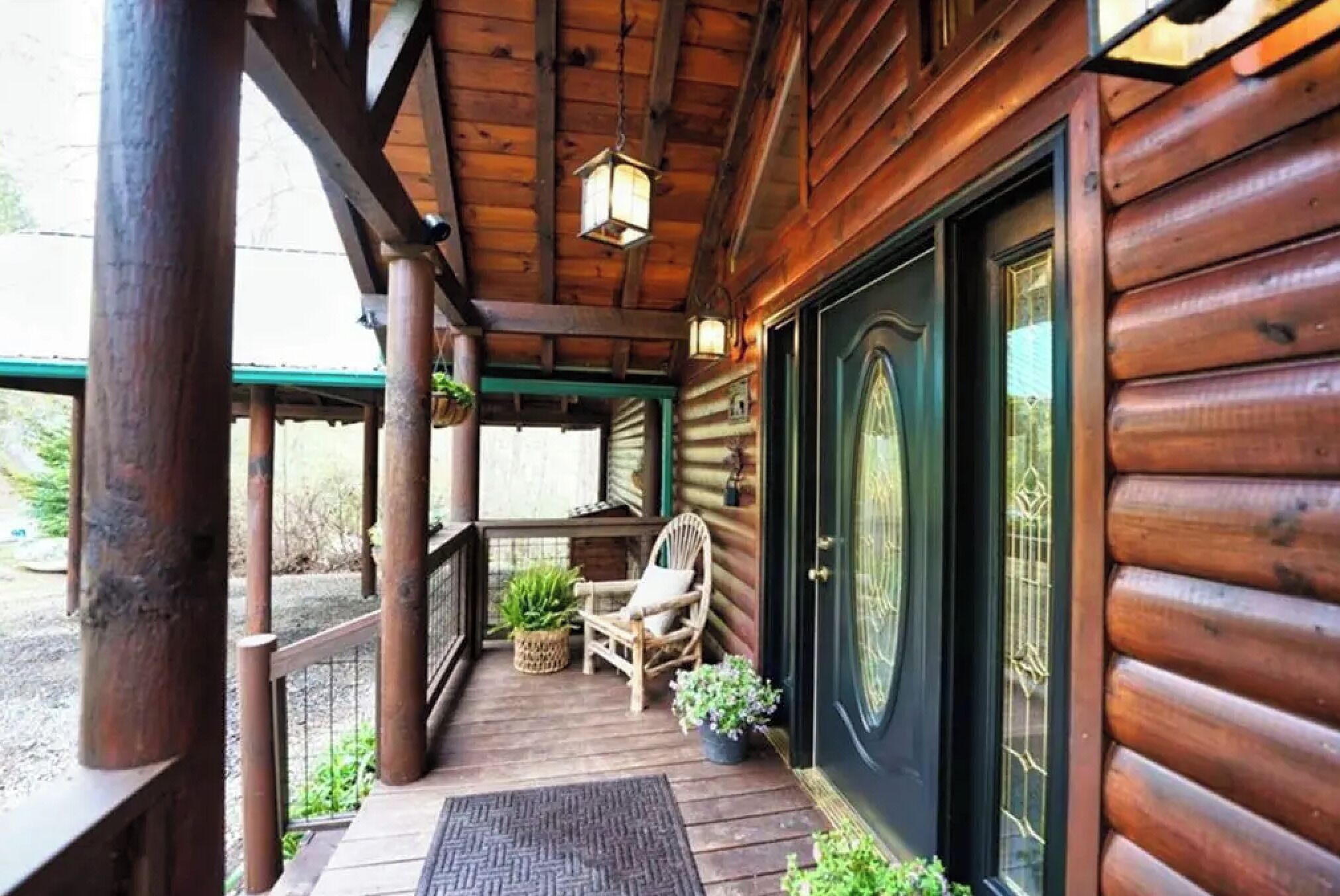 A wooden cabin with a porch, a chair, and a door.