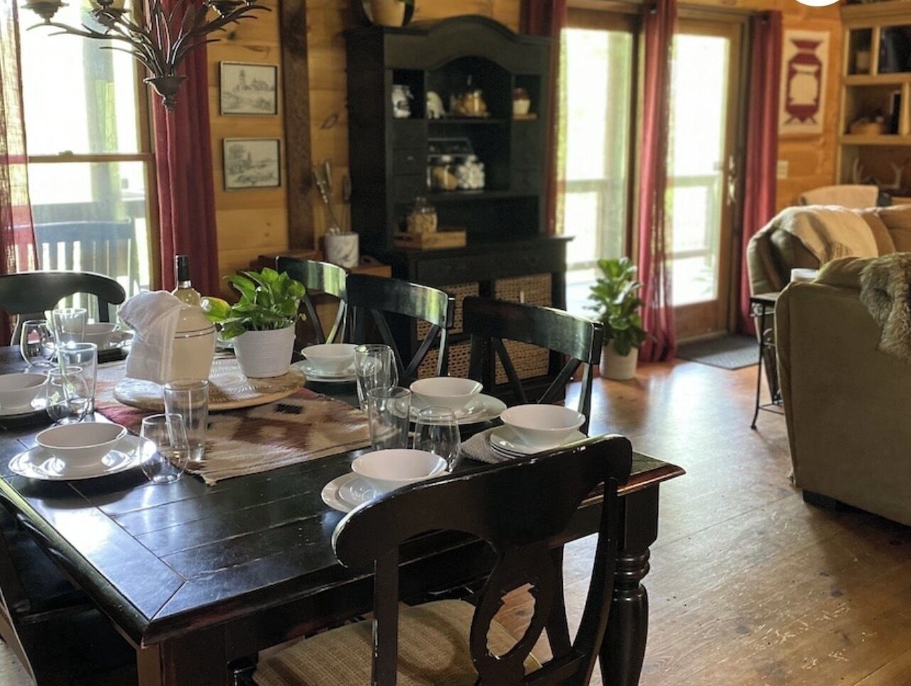 Un'area pranzo con un tavolo di legno apparecchiato per quattro persone, circondato da sedie, e un armadietto di legno scuro sullo sfondo.