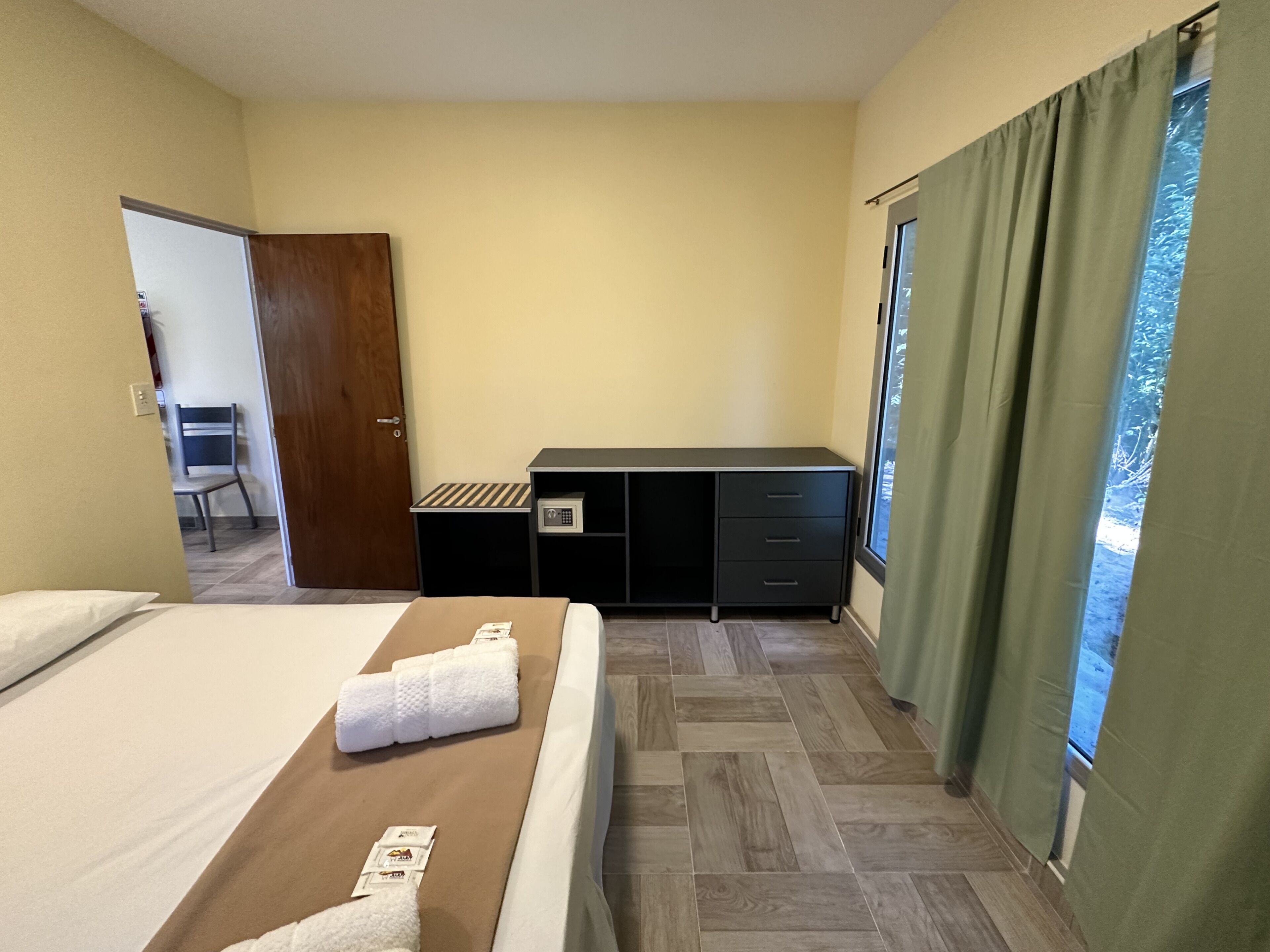 A hotel room with a bed, a desk, a chair, and a view of the outdoors.
