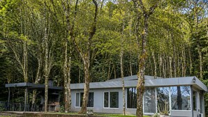 A modern house with a flat roof, large windows, and a stone foundation. - Eco Lodge de la Selva (San Salvador de Jujuy)