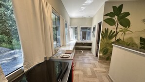 A modern kitchen with a large window, a flat-screen TV, and a tropical mural on the wall. - Eco Lodge de la Selva (San Salvador de Jujuy)