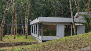A modern building with large windows, surrounded by trees and a grassy area. - Eco Lodge de la Selva (San Salvador de Jujuy)