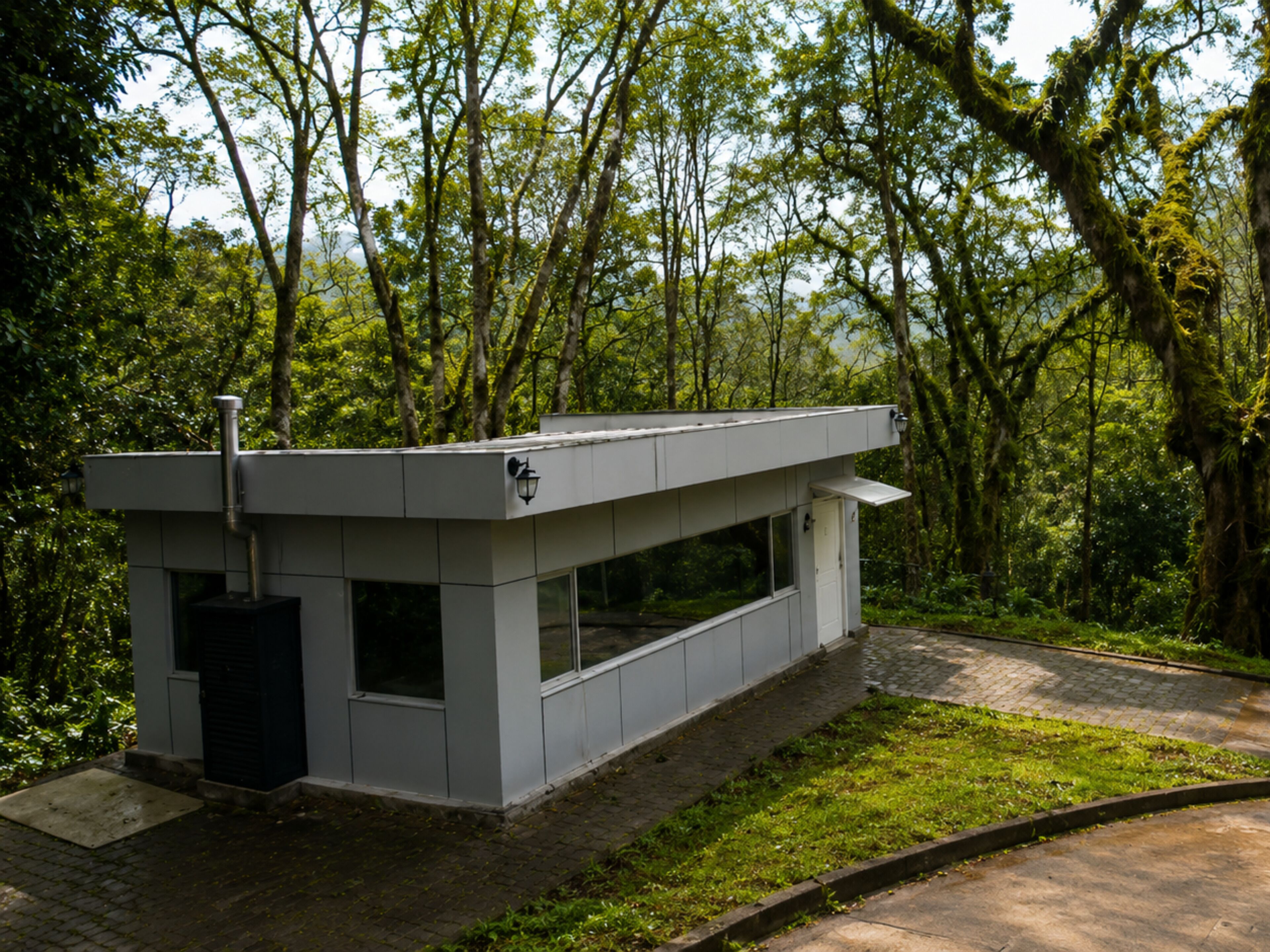 A modern, minimalist building with a flat roof, large windows, and a small entrance.