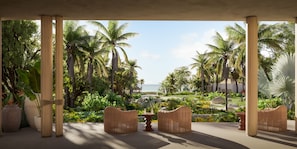 A covered outdoor seating area with wicker furniture, a small table, and a view of a tropical landscape with palm trees and a body of water. - Omni Pontoque Resort At Punta De Mita (Punta de Mita)