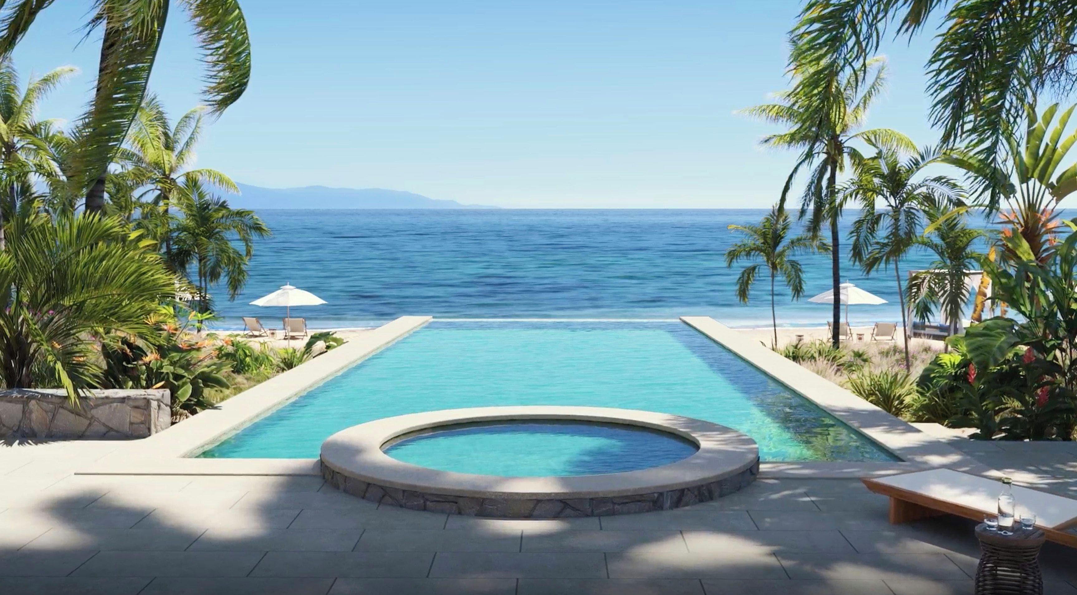 A rectangular swimming pool with a hot tub in the center, surrounded by lounge chairs and umbrellas, with a view of the ocean and palm trees.