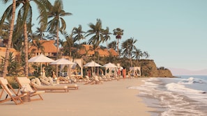 A beach resort with sun loungers, umbrellas, and thatched-roof buildings. - Omni Pontoque Resort At Punta De Mita (Punta de Mita)
