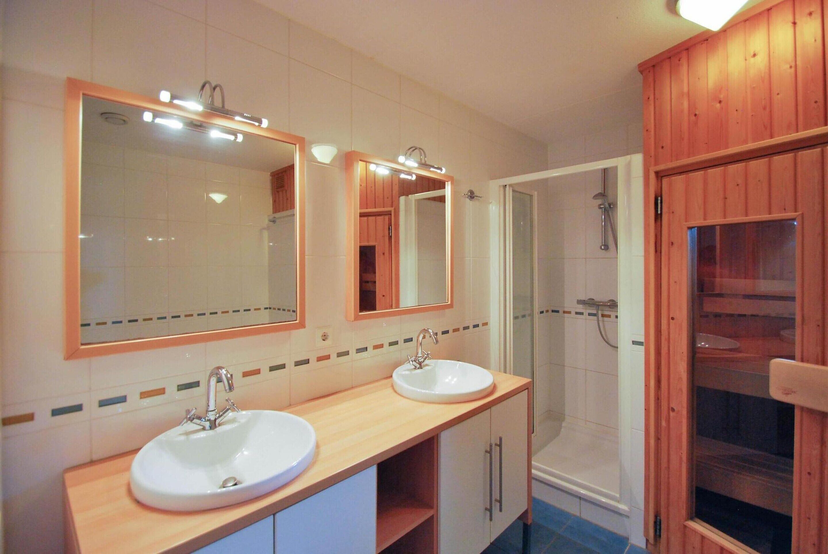 Ein Badezimmer mit zwei Waschbecken, einer Dusche und Holzausstattung.