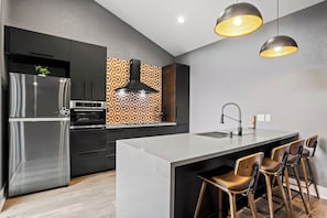 Eine moderne Küche mit einer zentralen Kochinsel, Edelstahlgeräten und einer gemusterten Spritzschutzwand.