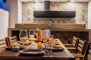 Una mesa de comedor dispuesta con platos, vasos y una botella, rodeada de sillas.