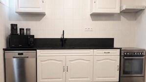 A kitchen with white cabinets, a black countertop, a stainless steel dishwasher, a stove, and a microwave.