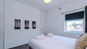 A bedroom with a bed, a window with a view, and three wall-mounted artworks. - Stylish 2 Bedroom Home Sleeps 4 (St Helens)