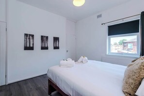 Ein Schlafzimmer mit einem Bett, einem Fenster mit Blick und drei an der Wand befestigten Kunstwerken.