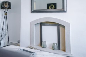 Una habitació amb una llar de foc, un mirall i una làmpada de peu.