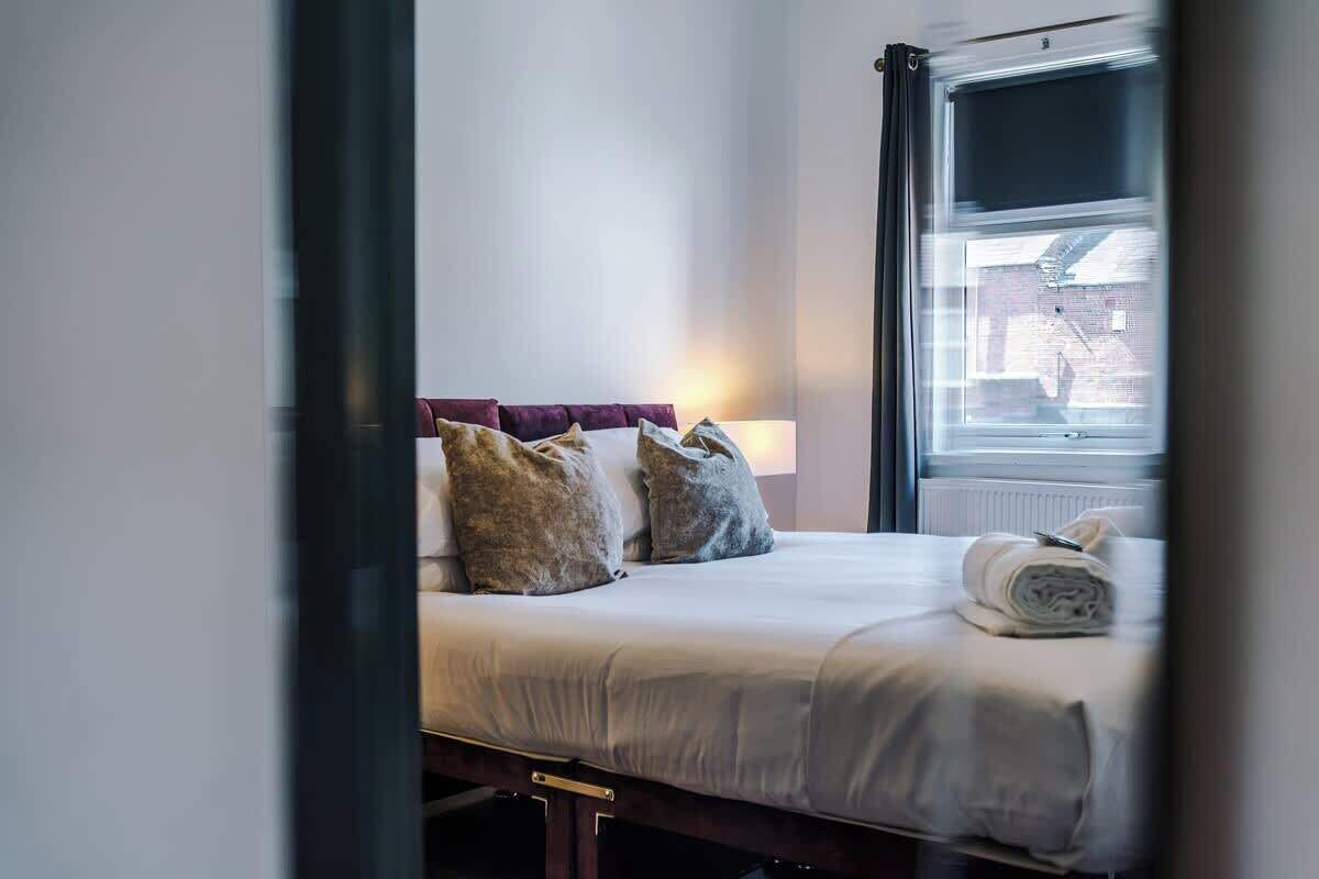 A hotel room with a bed, pillows, a window, and a view of the outside.