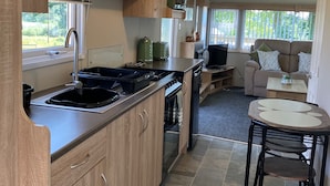 Una cocina compacta con armarios de madera, horno empotrado y comedor con una pequeña mesa y sillas.