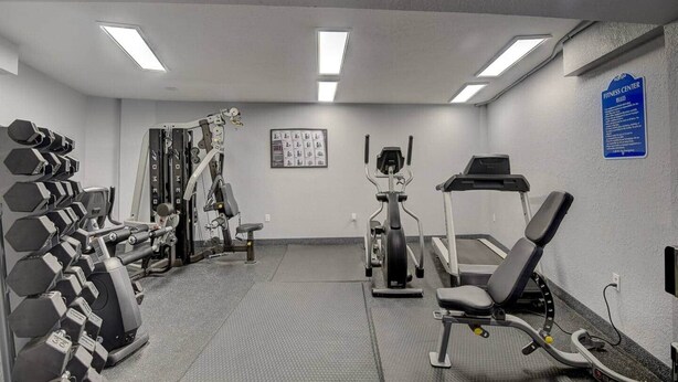 Ett gym med olika typer av träningsutrustning, inklusive hantlar, en styrketräningsmaskin och konditionsmaskiner.