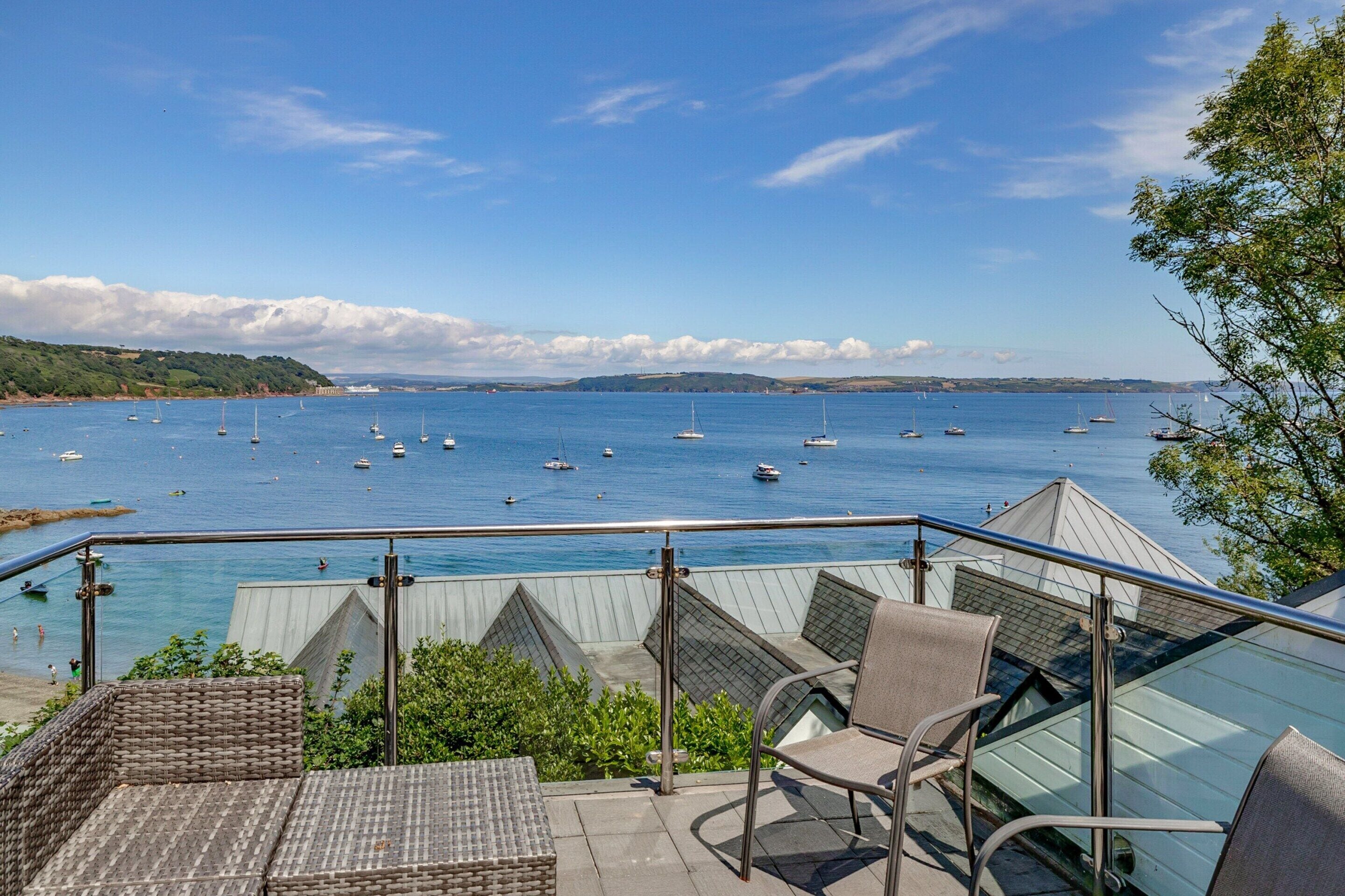 A terrace with wicker furniture overlooking a marina with boats.