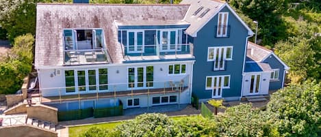 A two-story house with a balcony, large windows, and a well-maintained garden.