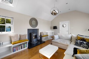 A modern living room with a fireplace, sofa, coffee table, and a bookshelf. - Cawsand Waterfront House With Pool (Torpoint)