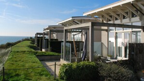 A modern house with a glass facade, a covered patio, and a view of the sea. - Villa With Panoramic Water Views (Makkum)