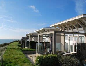 A modern house with a glass facade, a covered patio, and a view of the sea. - Villa With Panoramic Water Views (Makkum)