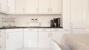A modern kitchen with white cabinets, a black countertop, a coffee maker, and a toaster. - Villa With Panoramic Water Views (Makkum)
