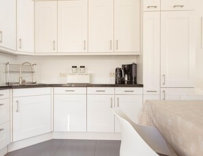 A modern kitchen with white cabinets, a black countertop, a coffee maker, and a toaster. - Villa With Panoramic Water Views (Makkum)