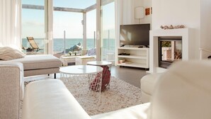 A modern living room with a large glass door leading to a balcony, a flat-screen TV, and a fireplace. - Villa With Panoramic Water Views (Makkum)