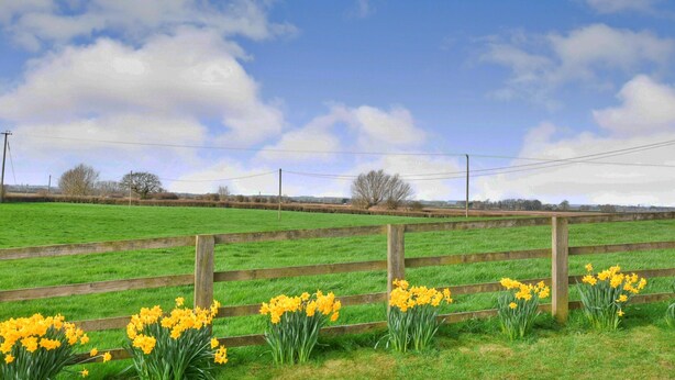 A rural landscape with a wooden fence, open fields, and a clear sky. - Family Cottage Near Wilsthorpe Beach (Driffield)