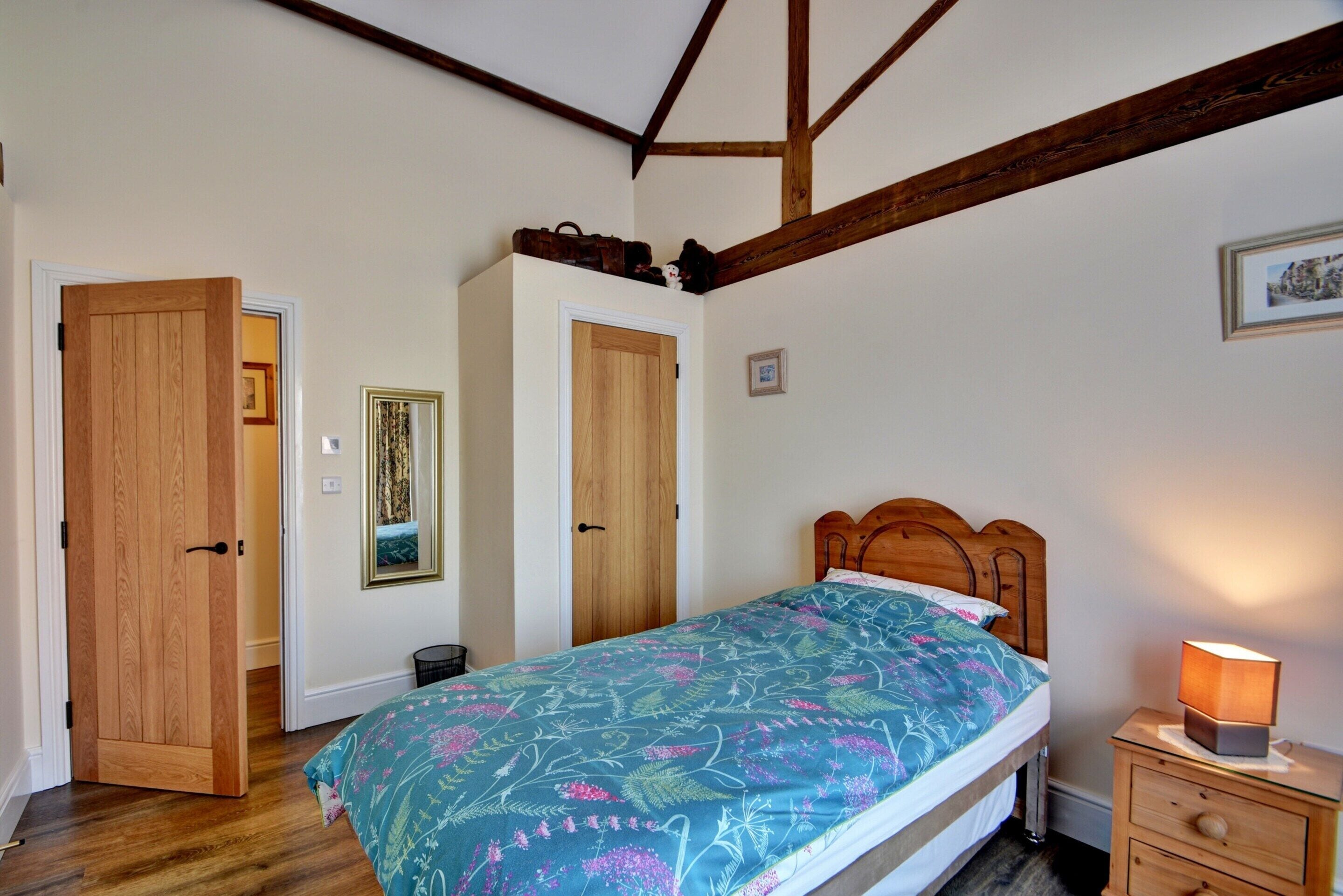 Une chambre à coucher avec un lit en bois, une table de chevet avec une lampe et deux portes.