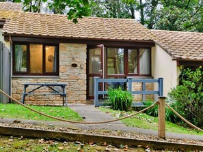 A stone cottage with a tiled roof, a wooden bench, and a rope barrier. - Cosy Cornwall Bungalow for 4 (St Ives)