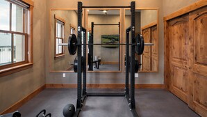 Una palestra con una panca per squat, bilancieri e uno specchio che riflette l'ambiente.