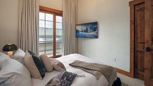 Una camera d'albergo con un letto, una finestra con tende, un quadro appeso al muro e una porta in legno.