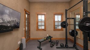 Ein Heimfitnessraum mit einer Bank, Kettlebells, einem Squat-Gestell und einem großen Spiegel.