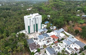 A residential area with a prominent multi-story building, smaller houses, and dense greenery. - Tranquil 2-bedroom apartment with AC in charming Thundathil (Thundathil)