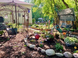 A garden with a gazebo, seating, and a variety of plants.