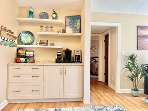 A kitchen with white cabinets, a coffee maker, and various kitchen items on the countertop.