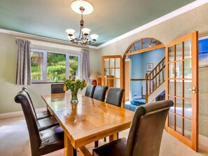 A dining room with a wooden table, six chairs, a vase with flowers, and a chandelier. - Ocean-view Manor With Jacuzzi (Torquay)